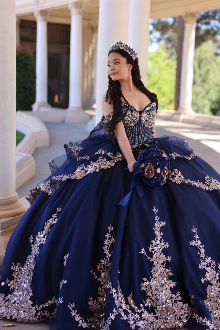 Quinceañera in a navy and gold gown holding a bouquet