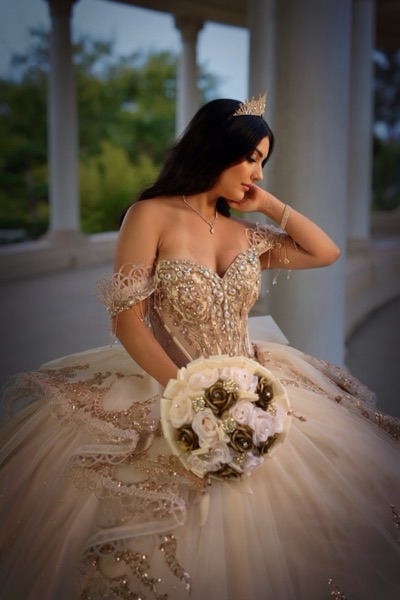 Quinceañera portrait in a champagne and gold gown with a cream rose bouquet